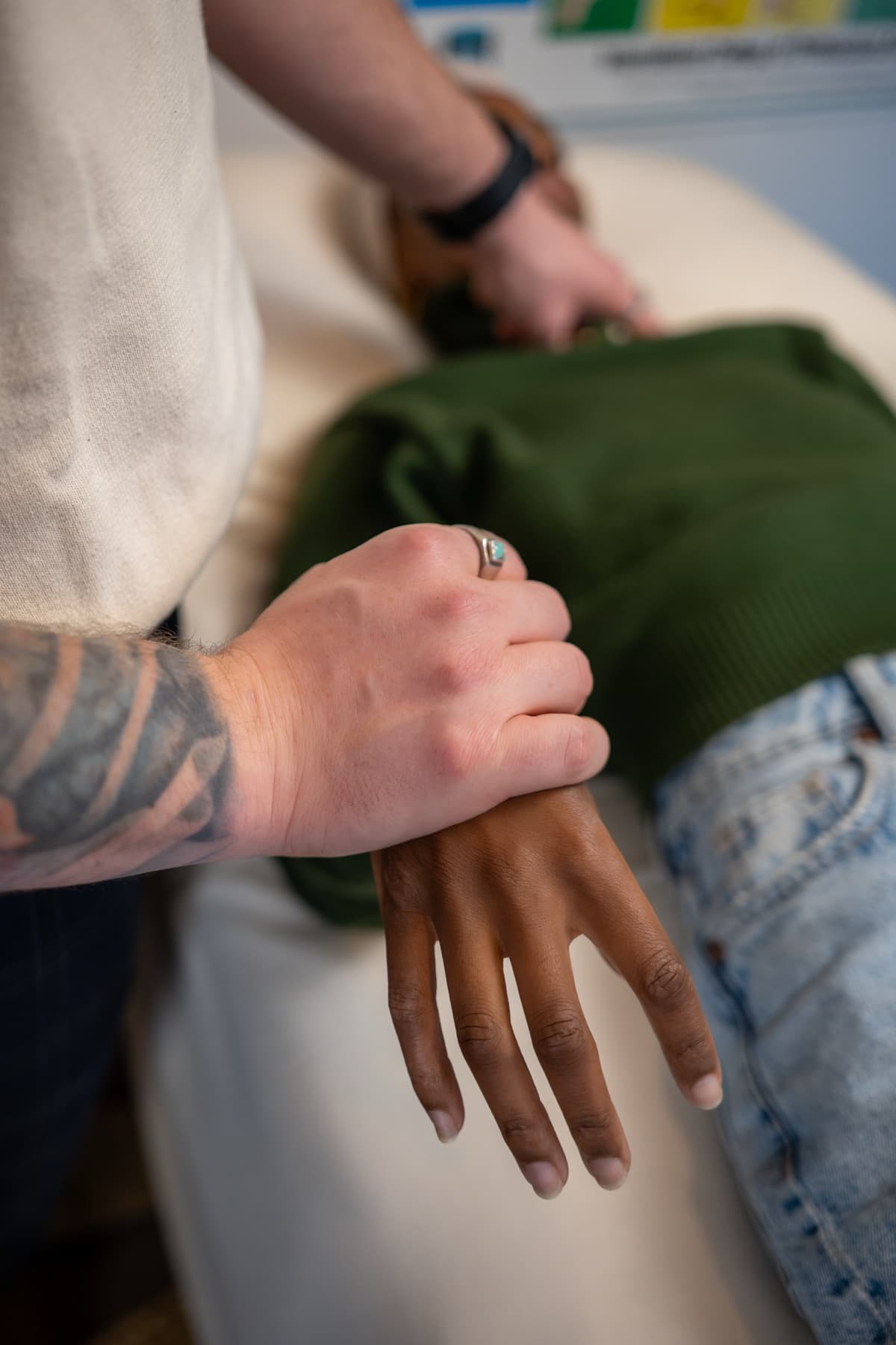 Close-up of PKP kinesiology muscle monitoring, the practitioner's hand holding a client's wrist on the treatment table.