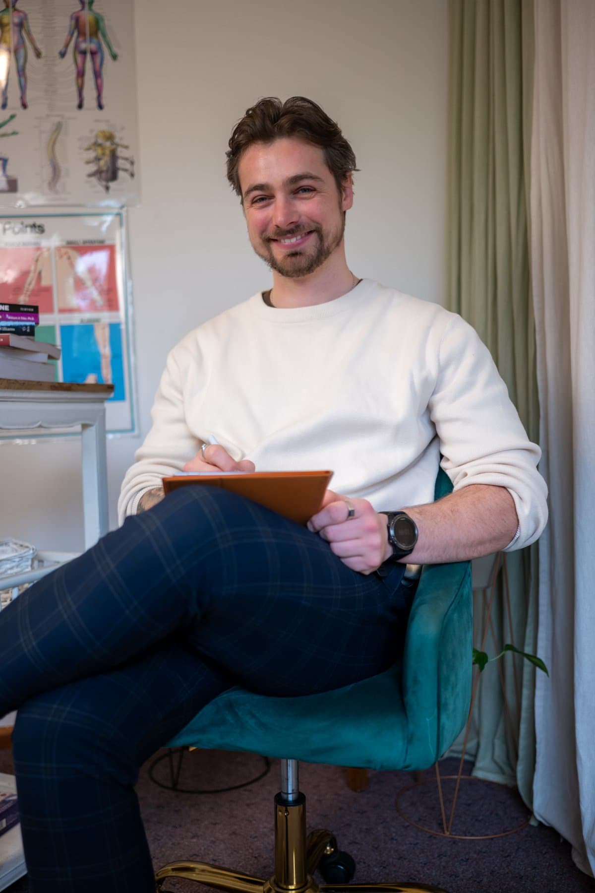 Vildan Alihodzic, PKP Kinesiologist, seated in his Moorabbin clinic chair with a notepad, smiling at the camera