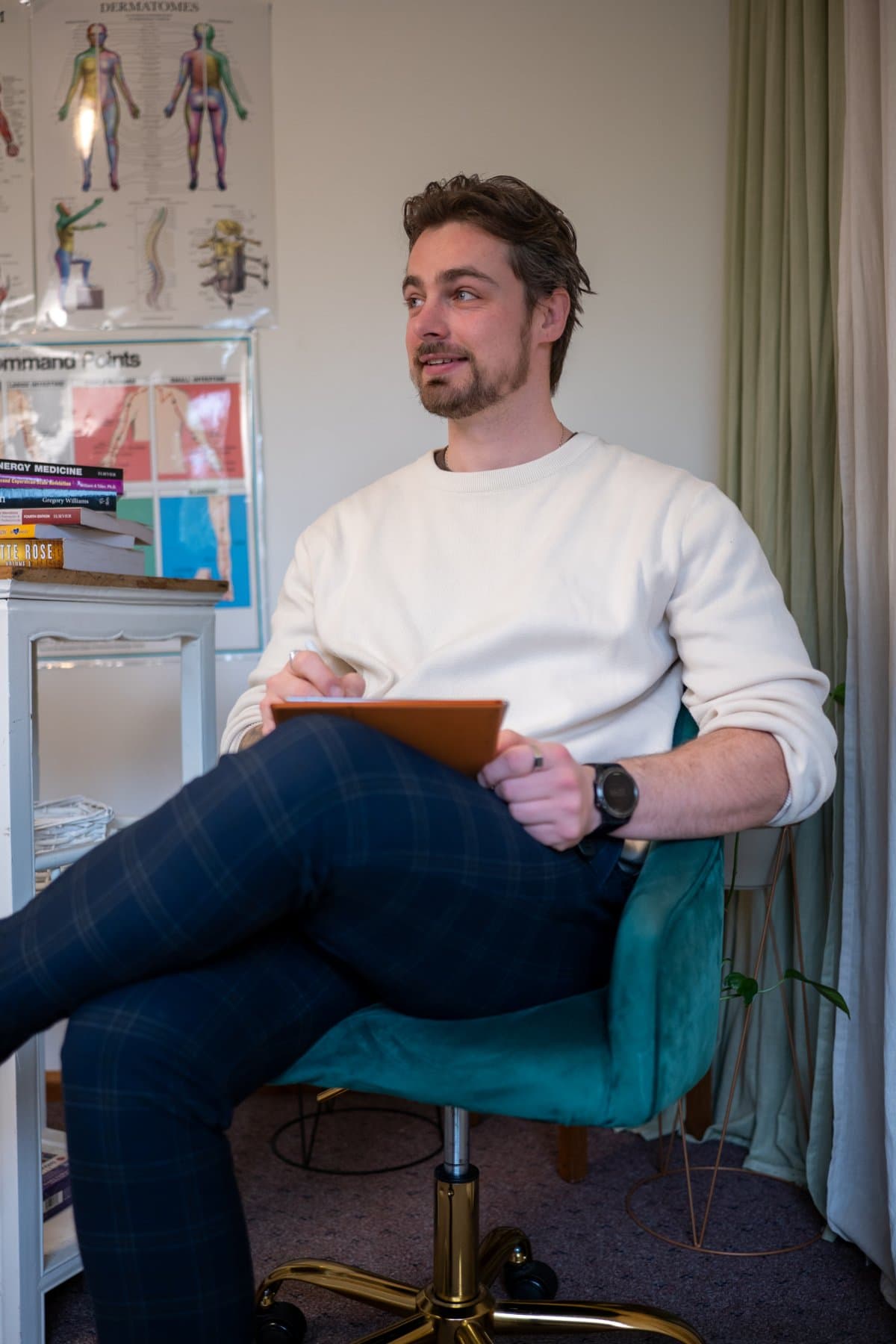 Vildan Alihodzic seated in his Moorabbin clinic, notepad on his knee, looking across the room