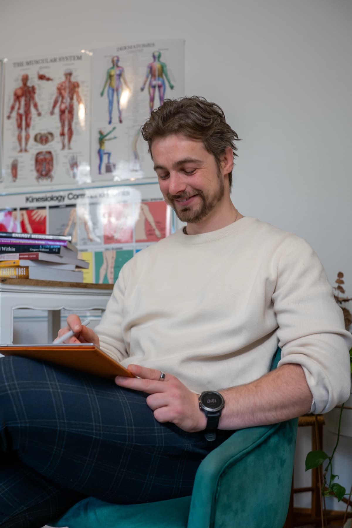 Vildan Alihodzic looks down and smiles while taking notes, muscular-system charts on the wall behind him.