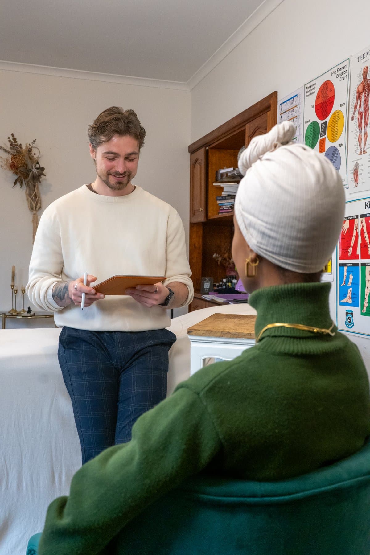 Vildan Alihodzic standing with a clipboard, talking a client through her session notes at Intelligentle Healing in Moorabbin